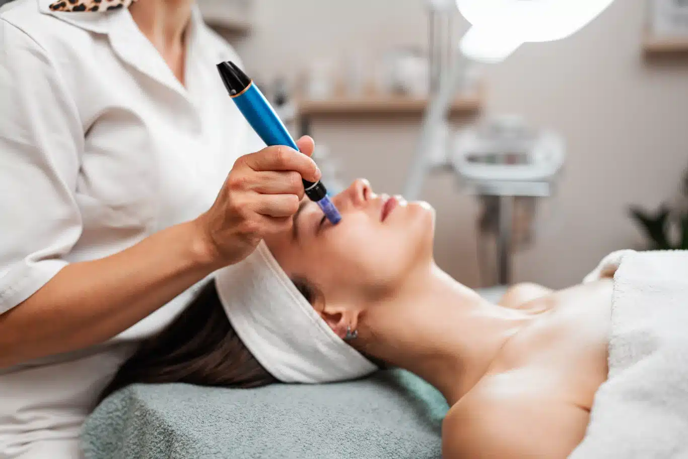 A professional cosmetologist uses a dermapen for a microneedling facial procedure